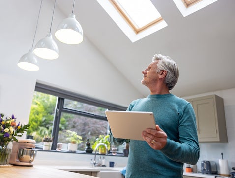 A Man Is Controlling Dim Lights in His Smart Home Using a Digital Tablet