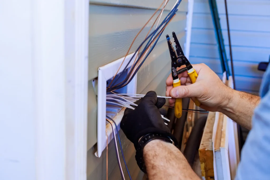 Electrician installing and stripping electrical wires in outdoor panel box in San Jose, CA